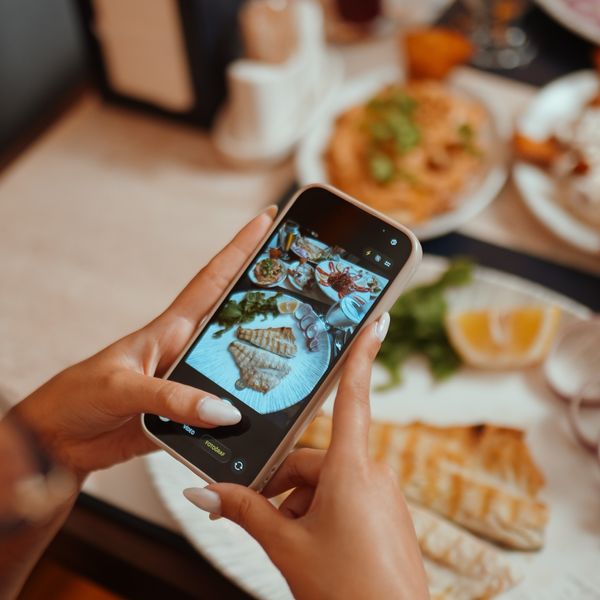 Sofradaki ızgara balık tabağının telefonla fotoğrafını çeken misafir