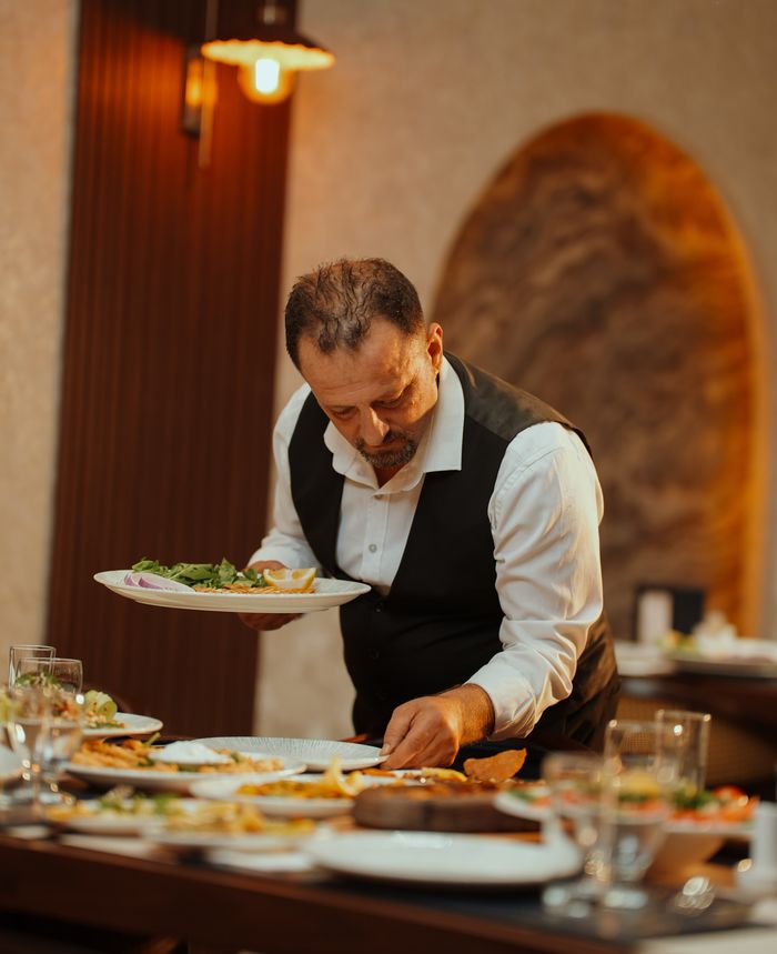 Kuzey Balık'ta garson, meze ve balık tabaklarıyla donatılmış sofraya servis yapıyor